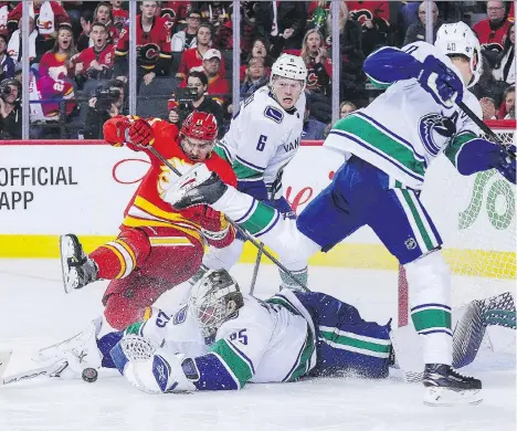  ?? GETTY IMAGES ?? Canucks goalie Jacob Markstrom dives to collect the loose puck against the Flames on Saturday night in Calgary. While some NHL puck stoppers are complainin­g that new equipment rules are offering goalies less protection, Markstrom says it hasn’t been an issue for him.