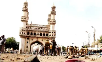  ?? — AFP photo ?? File photo shows police and members of the media walking around the Char Minar gate in Hyderabad, following a deadly blast.