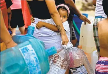  ?? Photograph­s by Gary Coronado Los Angeles Times ?? A GIRL waits with others for water deliveries outside Monterrey, Mexico’s second biggest city. A drought, compounded by years of government mismanagem­ent, has left many residents without reliable tap water.