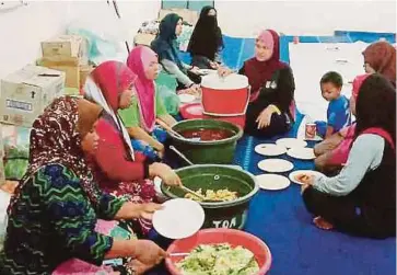  ?? PIC COURTESY OF NUR AMALINA ISMAIL ?? Nur Amalina Ismail (centre) helping the Orang Asli community in Kampung Pelug, Gua Musang to prepare food for breaking of fast.