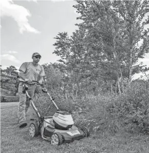  ?? MARLON CO/NEW YORK BOTANICAL GARDEN VIA AP ?? Tyler Campbell mows the grounds in front of the Enid A. Haupt Conservato­ry at the New York Botanical Garden in the Bronx borough of New York.