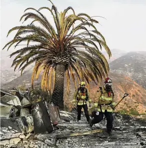  ?? — AP ?? All gone: Firefighte­rs walking among the ashes of a wildfire-ravaged home after turning off an open gas line on the property in Malibu.