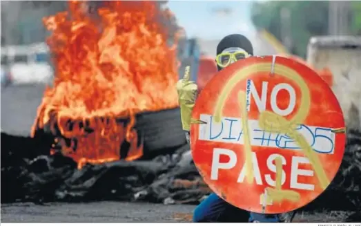  ?? ERNESTO GUZMÁN JR. / EFE ?? Un manifestan­te sostiene un aviso durante una protesta en Cali contra la política económica del Gobierno colombiano.