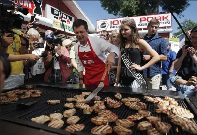  ?? John Locher The Associated Press ?? Pete Buttigieg helps cook Tuesday at the Iowa State Fair in Des Moines. He also addressed a Las Vegas convention by video.