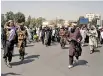  ??  ?? Taliban forces walk in front of Afghan demonstrat­ors