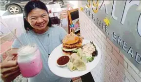  ?? PIC BY MUHAMMAD ZUHAIRI ZUBER ?? Eggxtra restaurant owner Gan Chai Yee holding up a plate of Nasi Lemak Burger and Bandung milkshake at her eatery in Melaka yesterday.