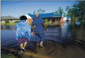  ??  ?? Soncia King and her husband, Patrick King, are seen in Lake Charles, La., Saturday as they walk through the flooded street to their home. Delta hit as a Category 2 hurricane with top winds of 100 mph before rapidly weakening over land.
