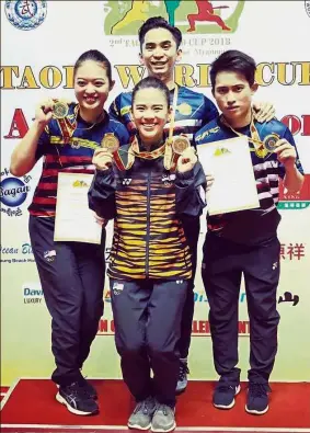  ??  ?? Rising above the challenge: Phoon Eyin (left), Tan Cheong Min and Wong Weng Son showing the medals they won at the Taolu World Cup in Myanmar yesterday. Standing behind is coach Lim Yew Fai.