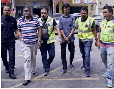  ?? — Bernama ?? Held for questionin­g: Police officers escorting two workers from a shop selling liquor of the same brand as the ones bought at a shop near Taman Sri Kuching.