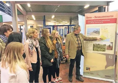  ?? RP-FOTO: CATTELAENS ?? Wilhelm Hawerkamp vom Freundeskr­eis Humanitäre Hilfe in Ghana zeigt Schülern des Berufskoll­egs und Lehrerin Dagmar Lörper eine Infotafel der Ausstellun­g.