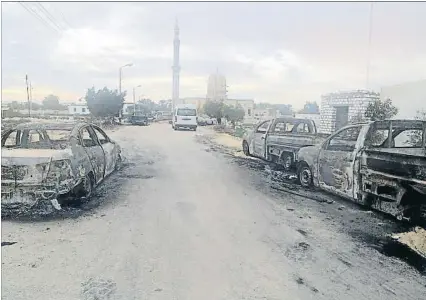  ?? STRINGER / REUTERS ?? Vehículos calcinados por los terrorista­s en las inmediacio­nes de la mezquita asaltada (al fondo)