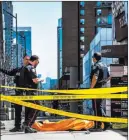  ?? Aaron Vincent Elkaim ?? The Associated Press Police officers stand by a body covered on the sidewalk in Toronto after a van mounted a sidewalk Monday, crashing into a crowd of pedestrian­s.