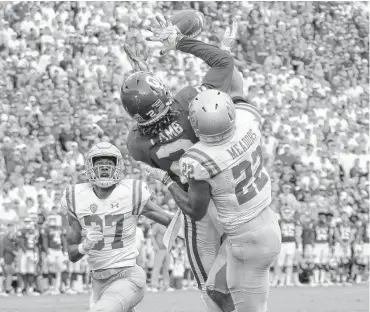  ??  ?? Oklahoma’s CeeDee Lamb catches a touchdown pass over UCLA’s Quentin Lake (37) and Nate Meadors (22) during the Sooners’ 49-21 win last Saturday in Norman. [PHOTO BY BRYAN TERRY, THE OKLAHOMAN]