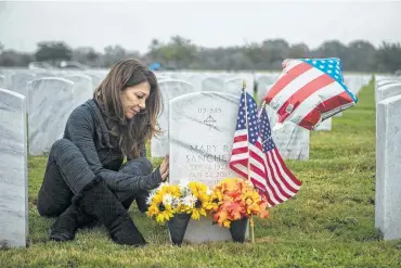  ?? Josie Norris / Staff photograph­er ?? IN SAN ANTONIO: Eva Sanchez touches the headstone of her father-in-law, Carlos Sanchez, and her mother-in-law, Mary Sanchez, as she visits their graves at Fort Sam Houston National Cemetery.