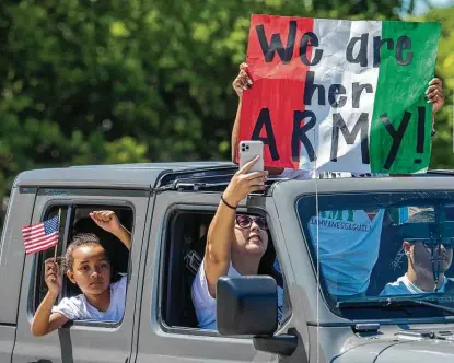  ?? Photos by Carlos Javier Sanchez / Contributo­r ?? Isa Prado, 15, holds a sign as Eliana Nzeedjang, 7, pumps her fist and Daniela Nzeedjang records video during a convoy honoring Vanessa Guillén, a missing soldier at Fort Hood whose remains were found last month near the post.