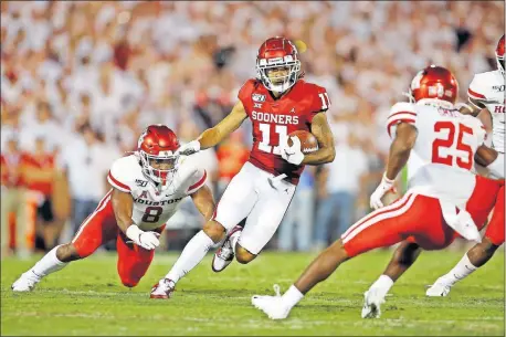  ?? [BRYAN TERRY/ THE OKLAHOMAN] ?? Oklahoma receiver Jadon Haselwood, center, runs past Houston's Chandler Smith, left, during Sunday night's game on Owen Field. Haselwood was one of seven true freshmen to play for the Sooners on opening night.