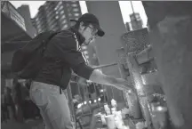  ?? DREW ANGERER VIA AFP ?? A man lights a candle during a vigil on Oct 8 for four homeless men who were killed in Chinatown in New York on Oct 5.