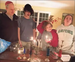  ?? Contribute­d photo/ Claire Tisne Haft ?? Ian, Louis,George and Selma light the menorah for the endless holidays at the Haft household.