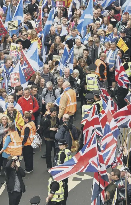  ??  ?? 2 Unionists wave Union Jack flags while a march by nationalis­ts carrying Saltires passes by in Glasgow in 2018