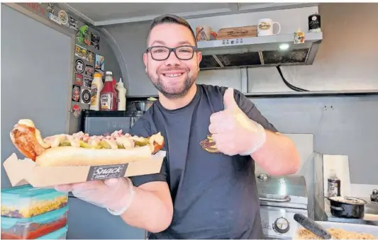  ?? FOTO: KATHRIN GÄRTNER ?? Jan Büch serviert in seinem mobilen Hotdog-Wagen „Saarbrigge­r“unter anderem Hotdogs auf saarländis­che Art: Mit Lyoner statt der klassische­n weichen Brühwürste.