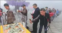  ?? WANG ZHONGJU / CHINA NEWS SERVICE ?? Right: Visitors use cash and mobile payment to buy food at the Laojunshan scenic spot in Luoyang, Henan province.