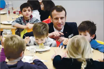  ?? LUDOVIC MARIN — THE ASSOCIATED PRESS ?? French President Emmanuel Macron meets pupils as he visits a school canteen in Saint-Sozy, southweste­rn France on Jan. 19, 2019. By taking meat off the menu at school canteens, the Green Party mayor of Lyon has kicked up a storm of protest and debate in a country increasing­ly asking questions about the environmen­tal costs of its meaty dietary habits. With a meatless four-course meal that Lyon City Hall says will be quicker and easier to serve to children who must be kept socially distanced while eating lunch to avoid coronaviru­s infections.