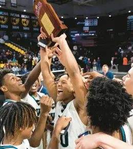  ?? STAFF FILE ?? Woodside player Jakobe Reed (30) hoists the Class 5 state championsh­ip trophy among teammates after Woodside defeated Patrick Henry of Roanoke 54-52 on March 11 at VCU. The Wolverines should contend to repeat.