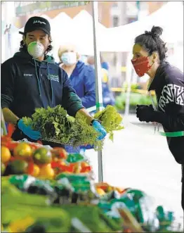  ?? NELVIN C. CEPEDA U-T ?? At the Farmers Market in Little Italy in April, Stephen Clark from J.R. Organics helped Lori Vanderlind­en, who is standing behind green tape, select produce.