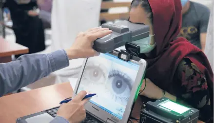  ?? RAHMAT GUL/AP ?? An employee scans the eyes of a woman for biometric data needed to apply for a passport at the passport office in Kabul, Afghanista­n.