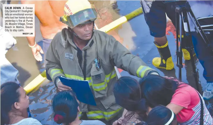  ?? MACKY LIM ?? CALM DOWN. A Davao City Central 911 firefighte­r tells an emotional woman who lost her home during yesterday's fire at Purok 26, Muslim Village, Times Beach in Matina, Davao City to stay calm.