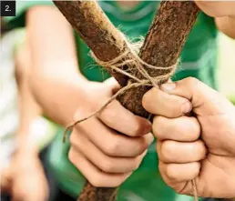  ??  ?? 2. Step 2: While Josh holds the crossed branches in place, Charlie wraps twine tightly around the poles and ties them firmly together.