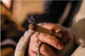  ?? Jeenah Moon/Bloomberg via Getty Images ?? A customer smokes while waiting in line outside the Housing Works Cannabis Co on the first day of legal recreation­al cannabis sales in New York on 29 December 2022. Photograph: