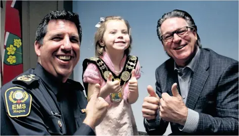  ?? KATHLEEN DRISCOL/SPECIAL TO THE STANDARD ?? Niagara Emergency Medical Services Chief Kevin Smith, left, and Niagara Region Chairman Alan Caslin share a moment with five-year-old Aisling DeGruchy Wednesday. The St. Catharines girl was awarded for helping save her mom’s life last month.