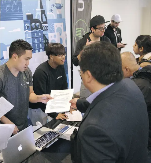  ?? PATRICK T. FALLON / BLOOMBERG NEWS ?? Uber staff accept resumés at an employment fair. Uber drivers are considered self- employed, on- demand workers.