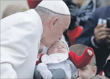  ??  ?? El papa Francisco besa a un bebé después de ofrecer su audiencia general semanal, celebrada ayer en la plaza de San Pedro de la Santa Sede