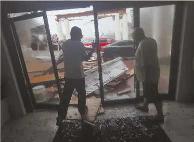  ?? AP PHOTO ?? SHATTERED: Hotel employs look through what is left of an entrance at an outside canopy that just collapsed as Hurricane Michael roared through Panama City Beach, Fla.