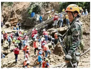  ?? — AP ?? Keeping watch: A Filipino trooper standing guard as search operations continue at the site where victims are believed to have been buried by a landslide triggered by Typhoon Mangkhut in Itogon.