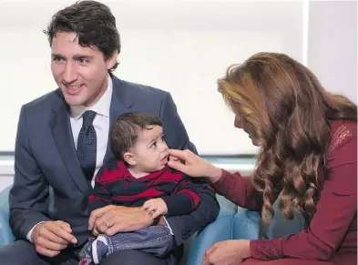  ?? JONATHAN HAYWARD / THE CANADIAN PRESS FILES ?? Prime Minister Justin Trudeau with a seven-month-old Syrian refugee in Vancouver in 2016. Since producing a report in 2016, the federal government has offered little in the way of updates on refugees’ fortunes in Canada.