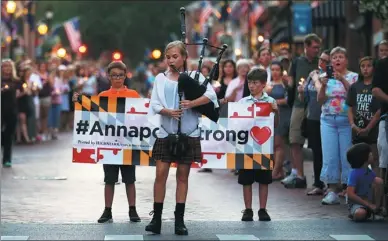  ?? LEAH MILLIS / REUTERS ?? People line the street as a piper plays Amazing Grace during a candleligh­t vigil in downtown Annapolis to honor the five people who were killed inside the Capital Gazette newspaper the day before in Annapolis, Maryland, on Friday.
