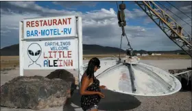  ?? JOHN LOCHER — THE ASSOCIATED PRESS ?? Grace Capati looks at a UFO display outside of the Little A’Le’Inn, in Rachel, Nev., the closest town to Area 51. The U.S. Air Force has warned people against participat­ing in an internet joke suggesting a large crowd of people “storm Area 51,” the top-secret Cold War test site in the Nevada desert.