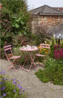  ??  ?? OPPOSITE Towering topiarised trees and crenellate­d yew hedges create a dramatic backdrop to planting at the historic Armoury THIS PAGE The L-shaped plot at Cleveland Place includes a charming pink
seating area and colourful planting, with bright blue...