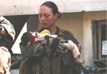  ?? AP ?? Marine Sgt. Nicole Gee holds a baby at Karzai Airport in Kabul, Afghanista­n. Sgt. Gee, of Sacramento, California, was killed in last week’s attack by ISIS-K.