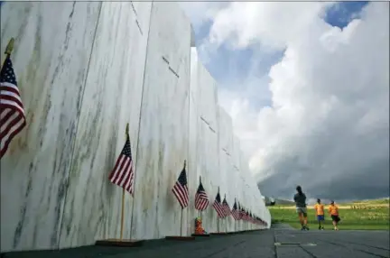  ?? GENE J. PUSKAR — ASSOCIATED PRESS FILE PHOTO ?? On May 31, visitors to the Flight 93 National Memorial pause at the Wall of Names honoring 40 passengers and crew members of United Flight 93 killed when the hijacked jet crashed at the site during the 9/11 terrorist attacks, near Shanksvill­e, Pa. Four shipping containers holding the remaining wreckage of United Flight 93 were buried near the Wall of Names in a private ceremony on June 21.