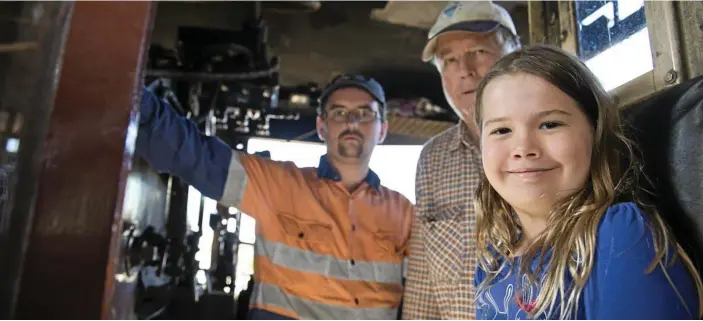  ?? PHOTOS: KEVIN FARMER ?? OLD STEAM TRAIN: Elizabeth Rixon gets up close with a steam train and sits in the driver’s seat with grandfathe­r Kevin Senz (centre) and operator Stephen Shepherd.