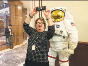  ?? Dan Haar / Hearst Connecticu­t Media ?? Terri Reid, assistant clerk at the General Assembly’s insurance committee, takes a selfie with the spacesuit at the Legislativ­e Office Building in Hartford on Thursday for the announceme­nt of an internatio­nal space summit in Hartford in May.