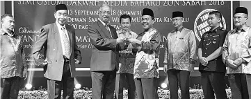  ??  ?? Uda (third left) representi­ng the Chief Minister, receiving a memento from Paimuzi (fourth right) during the launch of Sabah Zone 2018 Dakwah New Media Symposium yesterday.