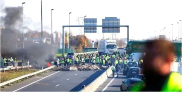  ??  ?? Demonstato­rs of ‘yellow vests’ (Gilets Jaunes) movement stand near a barricade blocking the traffic on Caen’s circular road on in Caen, western France, a day after a protest against high fuel prices. — AFP photo