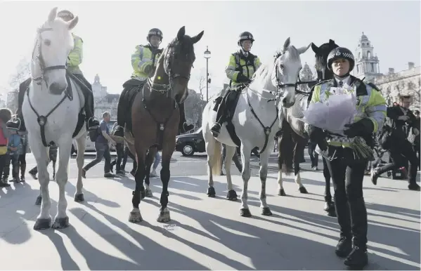  ??  ?? A police officer from a mounted team lays a bunch of flowers in tribute to PC Keith Palmer outside the Houses of Parliament in London yesterday