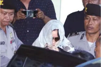  ??  ?? BALI: Australian drug smuggler Schapelle Corby covered her head with a scarf gets on a car as she leaves the parole office in Bali, Indonesia. — AP