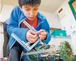  ??  ?? Sixth-grader Kairev Sharma adjusts a screw on his robot during the Science, Technology, Engineerin­g Arts and Math lunch club. Kairev, a member of the Robotics Club, is fine-tuning his robot for a state competitio­n.